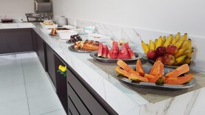 Un bufé con diversas frutas y pasteles.