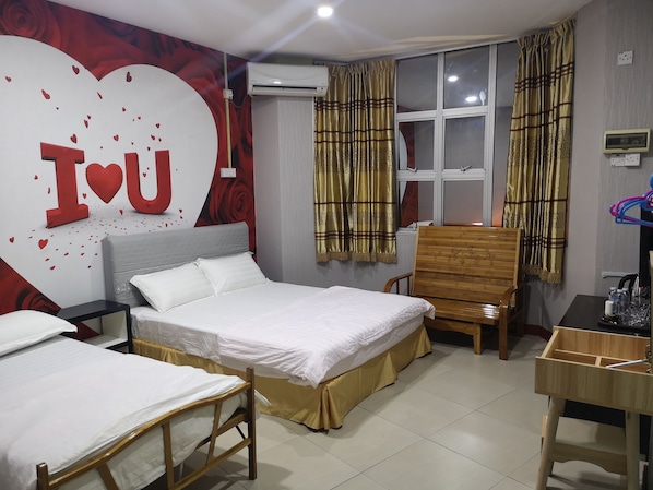 A hotel room with a large bed, a smaller bed, a wooden chair, a desk, and a window with curtains.