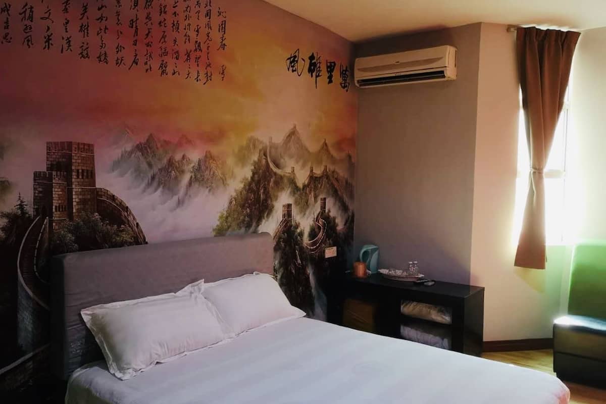 Habitación de hotel con cama, escritorio, silla y una pared decorada con caligrafía china y una pintura de montañas.