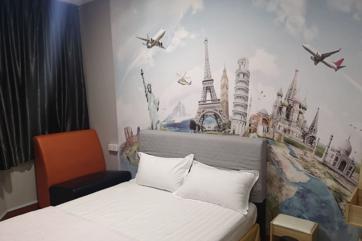 Una habitación de hotel con una cama, una silla y un mural en la pared con monumentos famosos.