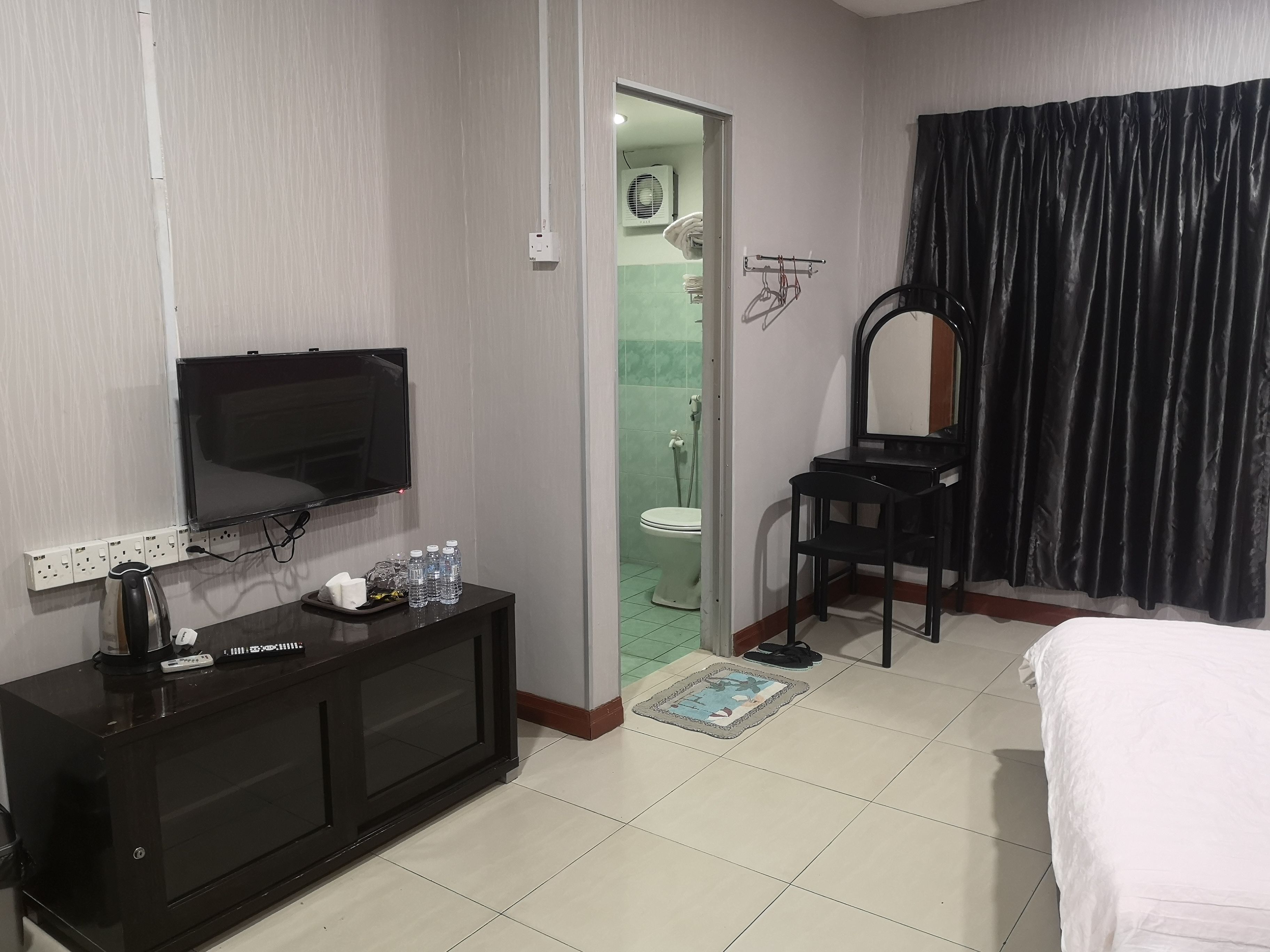 Une chambre d’hôtel équipée d’une télévision, d’un minibar, d’un bureau, d’une chaise, d’un lit, ainsi que d’une salle de bain avec des toilettes et une douche.