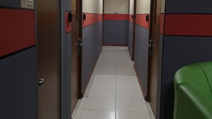 A corridor with doors on both sides, tiled floor, and a green object on the right. - Home Inn (Ipoh)