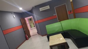 A room with a green sofa, a small table, a door, and an air conditioning unit. - Home Inn (Ipoh)