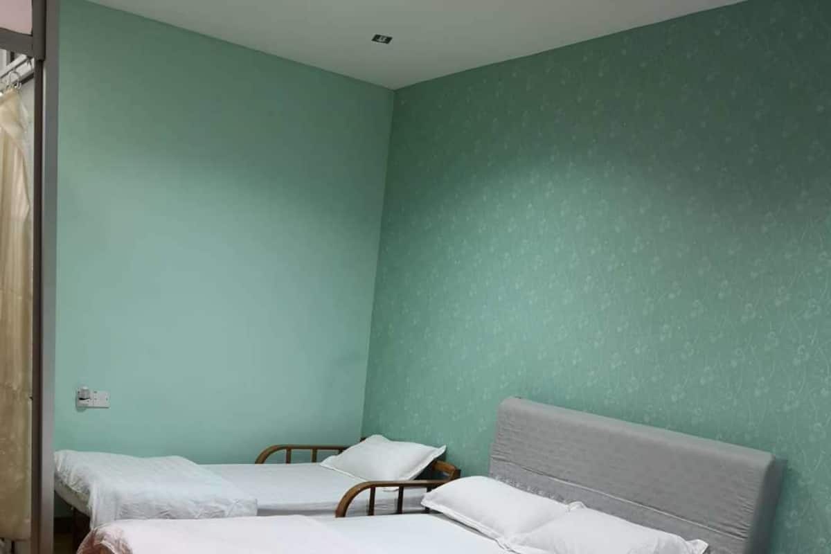 Una habitación con tres camas individuales, cabeceros de madera y suelo de madera.