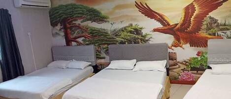 A hotel room with three single beds, a mural with a bird and tree, and an air conditioning unit.