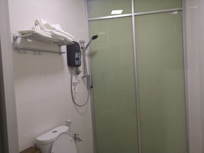 A bathroom with a toilet, a shower with a glass door, and a towel rack with folded towels.