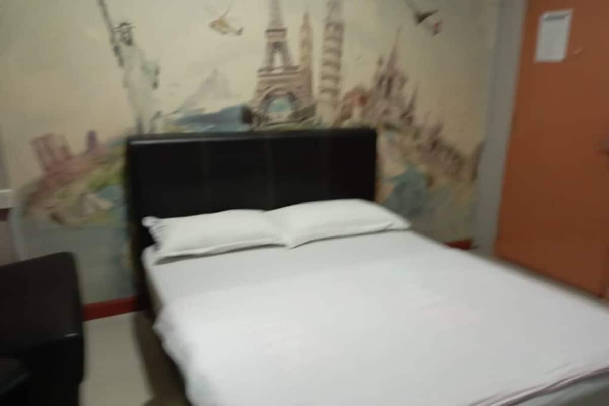 Una cama con ropa de cama blanca y un cabecero negro en una habitación con un mural de monumentos famosos en la pared.