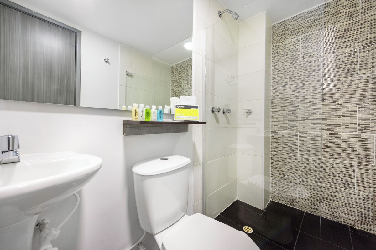 A modern bathroom with a white sink, toilet, and shower. There are toiletries on the countertop.