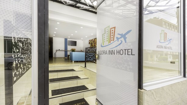 Un espace d’accueil d’hôtel comprenant un comptoir de réception, un comptoir bleu et un paillasson.