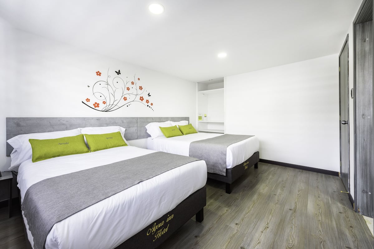 A hotel room with two beds, a decorative wall art, and a wooden floor.