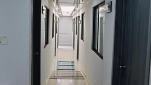 Un couloir moderne avec un sol carrelé, un éclairage encastré et une bouche d’aération centrale.