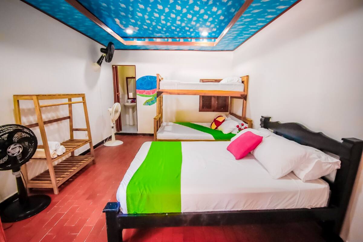 A room with bunk beds, a fan, a ceiling fan, and a wall decoration.
