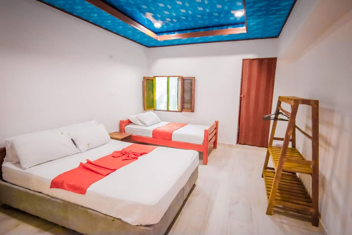 A room with two beds, a wooden ladder, a window with blinds, and a blue ceiling with a pattern.
