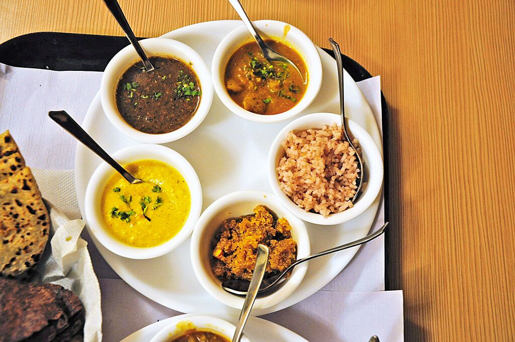 A tray with various bowls of food, including a bowl of soup, a bowl of rice, and a bowl of curry.