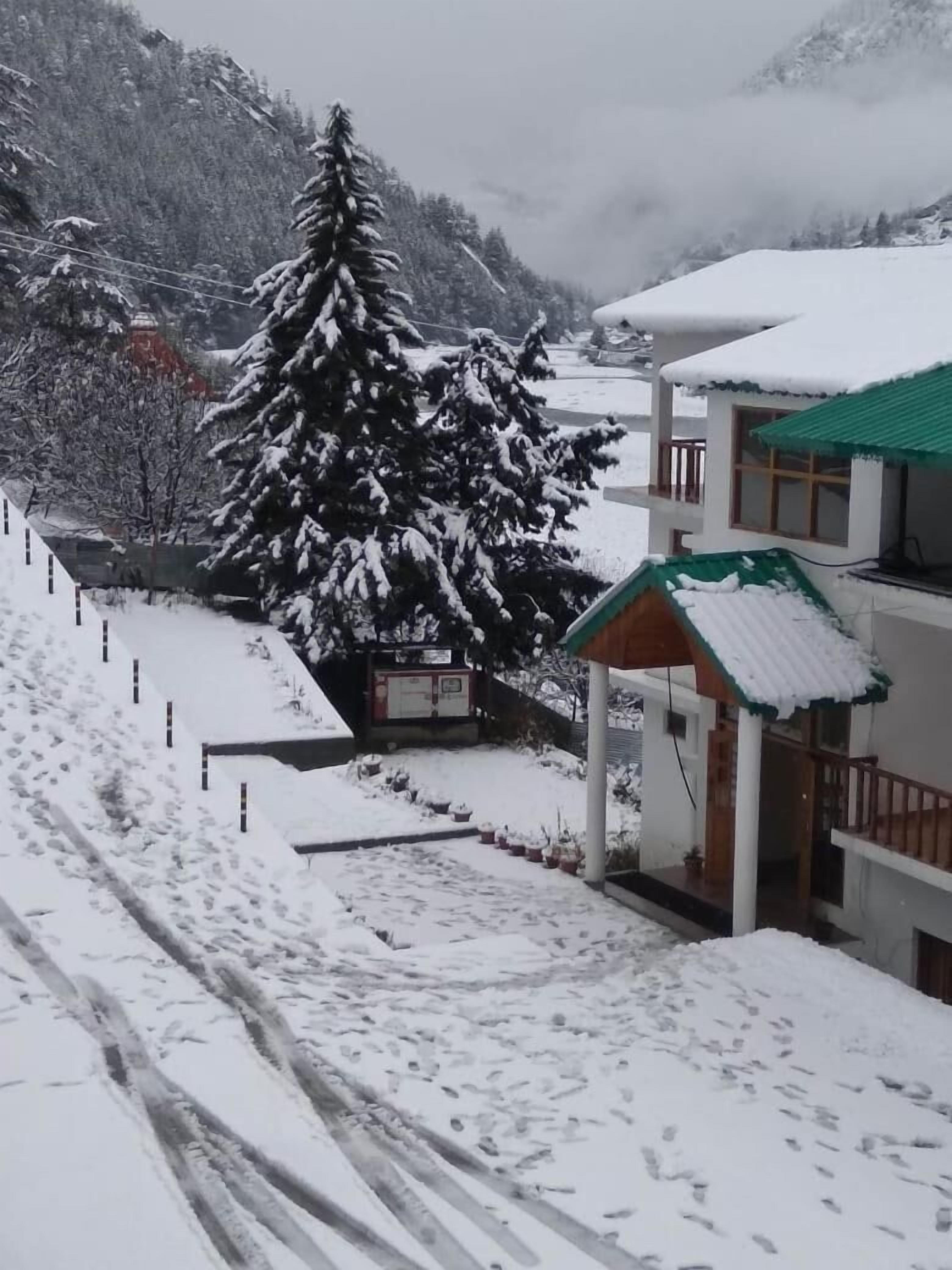 A snow-covered landscape with a building featuring a green roof and a small pavilion.