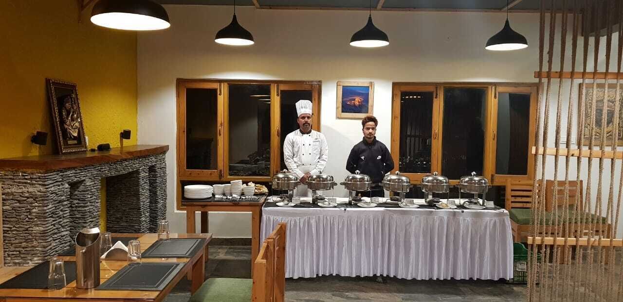Un ristorante con camino in pietra, diverse aree di servizio e una sala da pranzo con tavoli e sedie.
