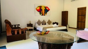 Une chambre d’hôtel avec un lit, une chaise en bois, une table en verre et un grand tableau représentant un éléphant accroché au mur.