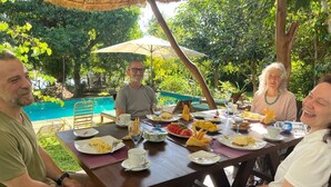 Un groupe de personnes est assis à une table en plein air, avec une piscine en arrière-plan.