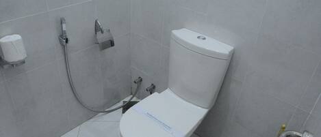 A bathroom with a white toilet, a shower, and a toilet paper holder on the wall.