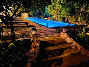 A swimming pool with steps leading up to it, surrounded by stone walls and potted plants. - Vimanra Hotel (Udawalawa)
