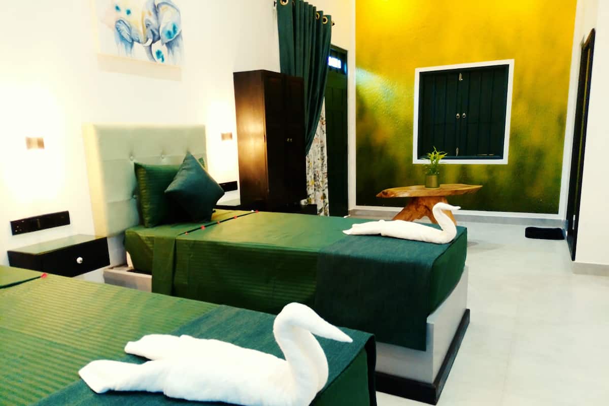 Una habitación de hotel con dos camas, una mesa de madera, un cuadro y una ventana con cortinas.