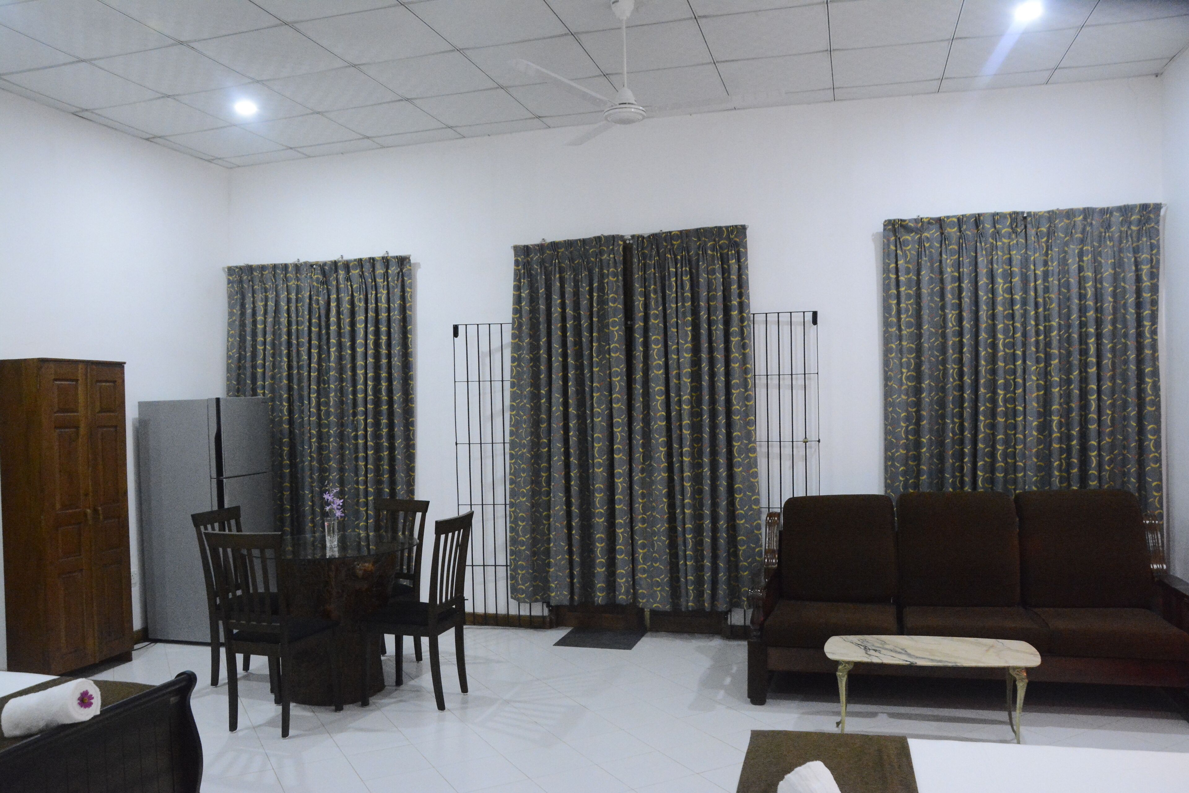 Una sala de estar con sofá, sillas, una mesa de centro, televisor y cortinas.