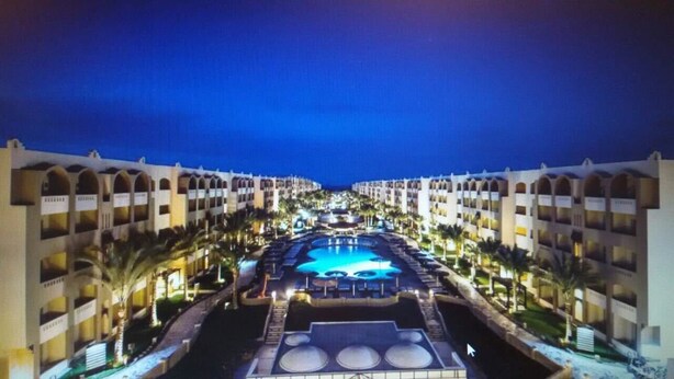Un hotel con un patio central que cuenta con una piscina, rodeado por edificios de varios pisos con balcones.