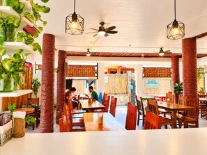 A restaurant with wooden tables and chairs, hanging plants, and ceiling fans. - Guanna's Place Room and Resto Bar (Daanbantayan)