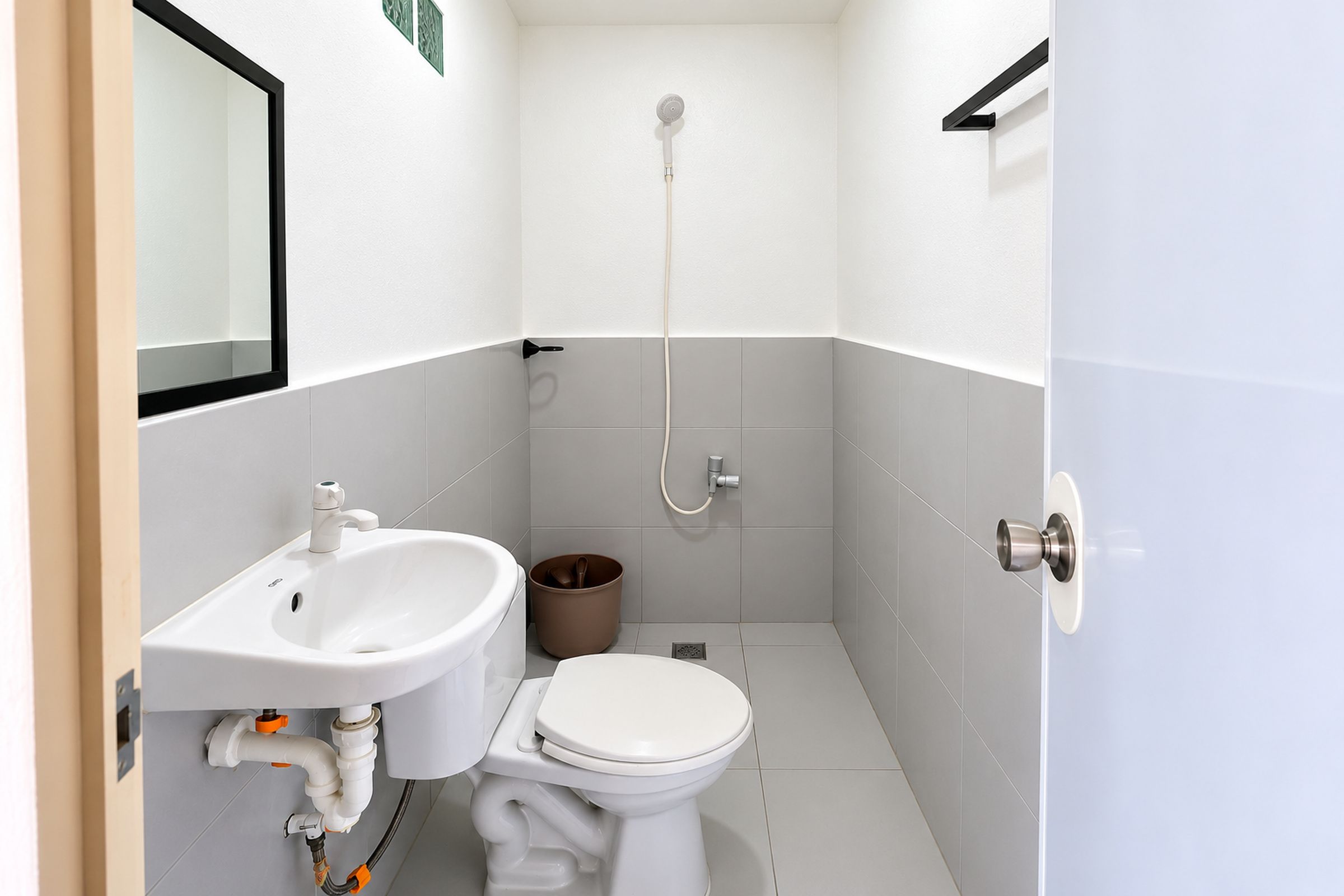 A small, modern bathroom with a white sink, toilet, and shower.