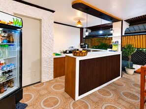 A modern kitchen with a built-in refrigerator, a wooden counter, and a patterned floor. - Guanna's Place Room and Resto Bar (Daanbantayan)
