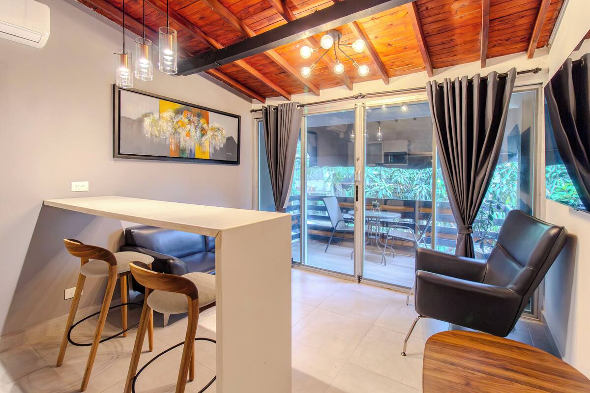 Una habitación moderna con comedor, sofá, sillón y mesa.