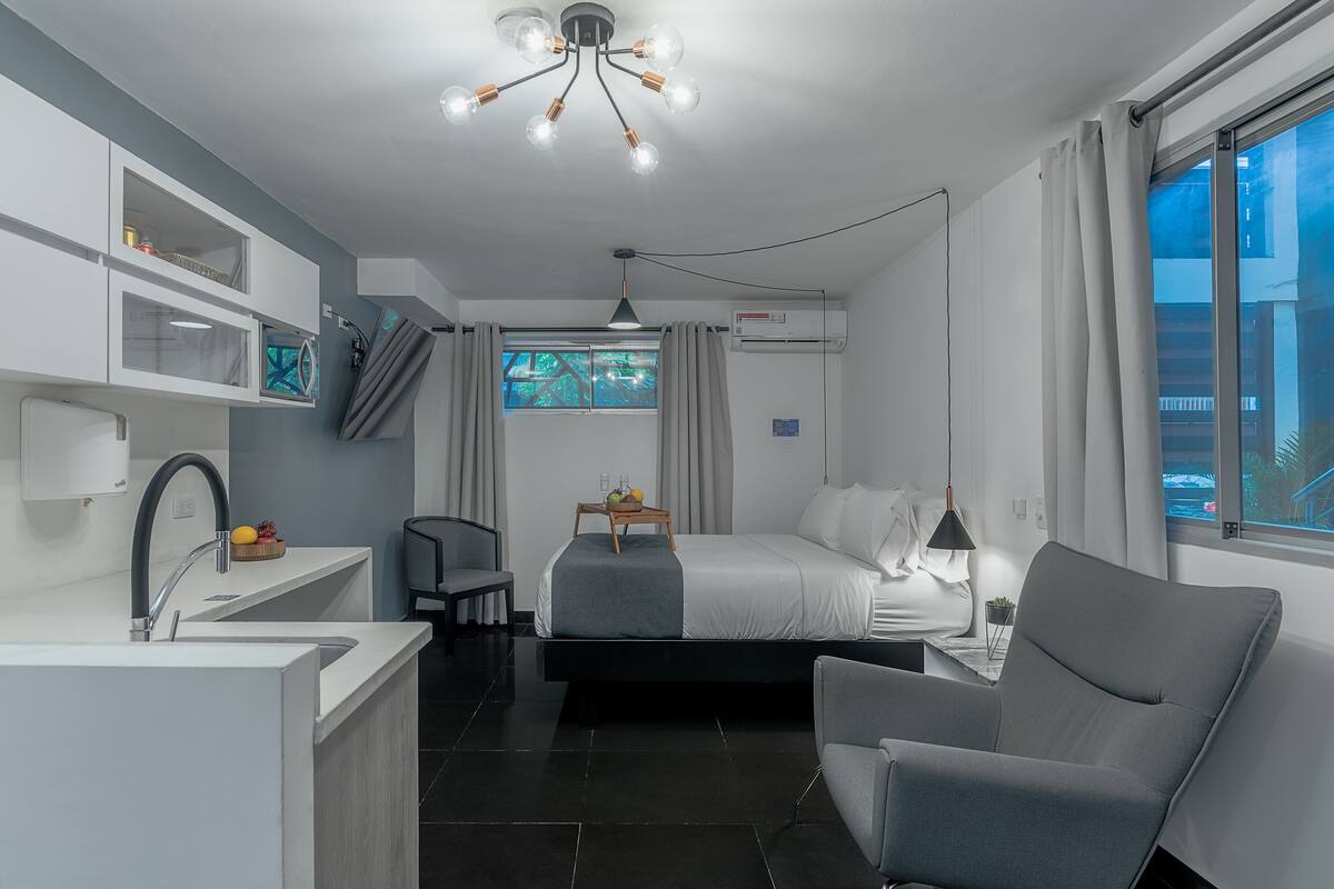 Habitación de hotel moderna con cama, escritorio, silla, baño y vistas al exterior.