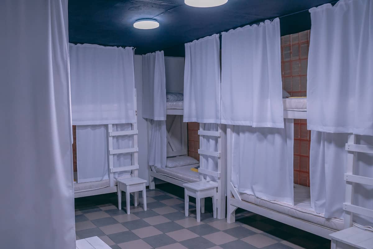 A room with bunk beds, white curtains, and a checkered floor.