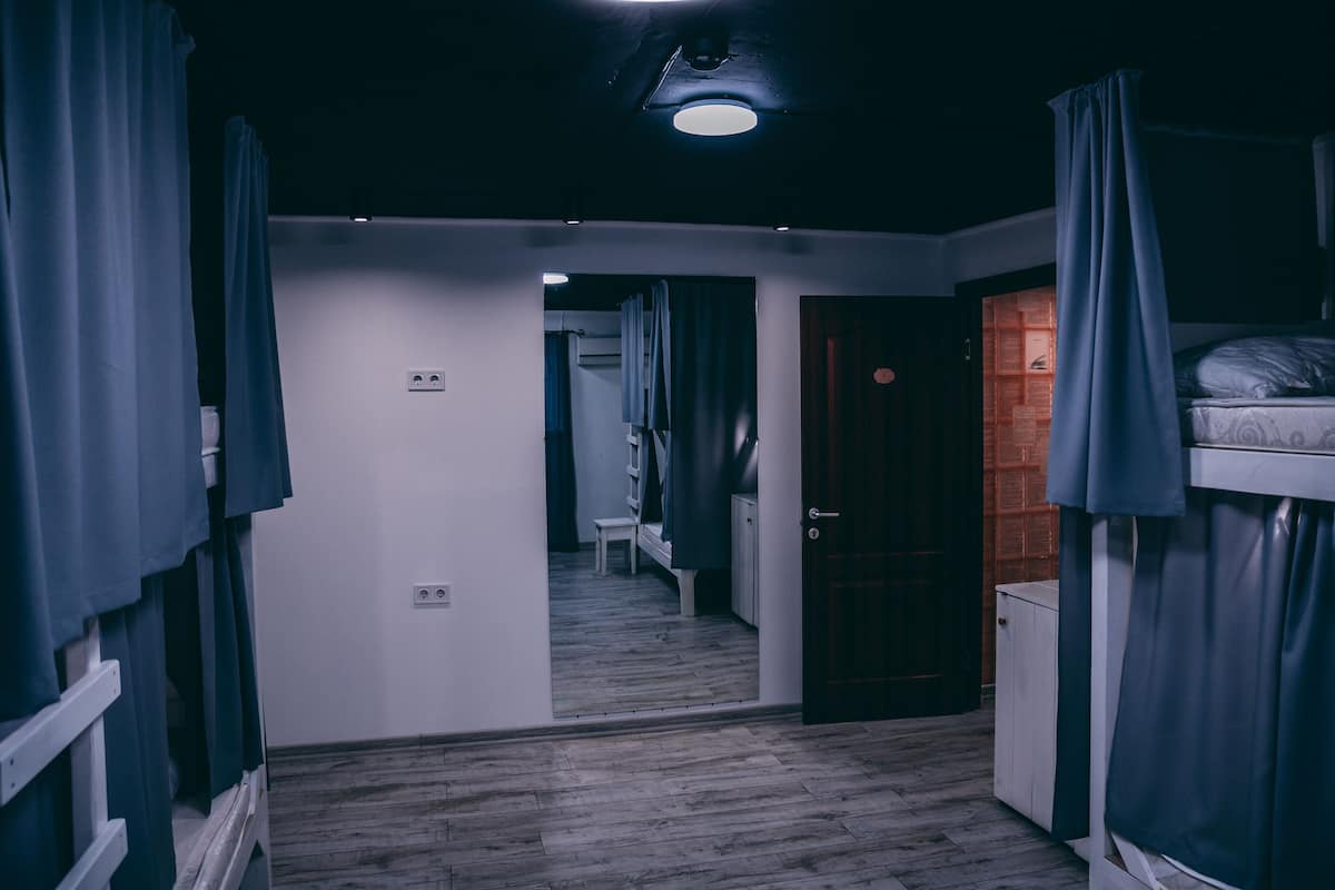 A room with bunk beds, a door, a bench, and a small table.