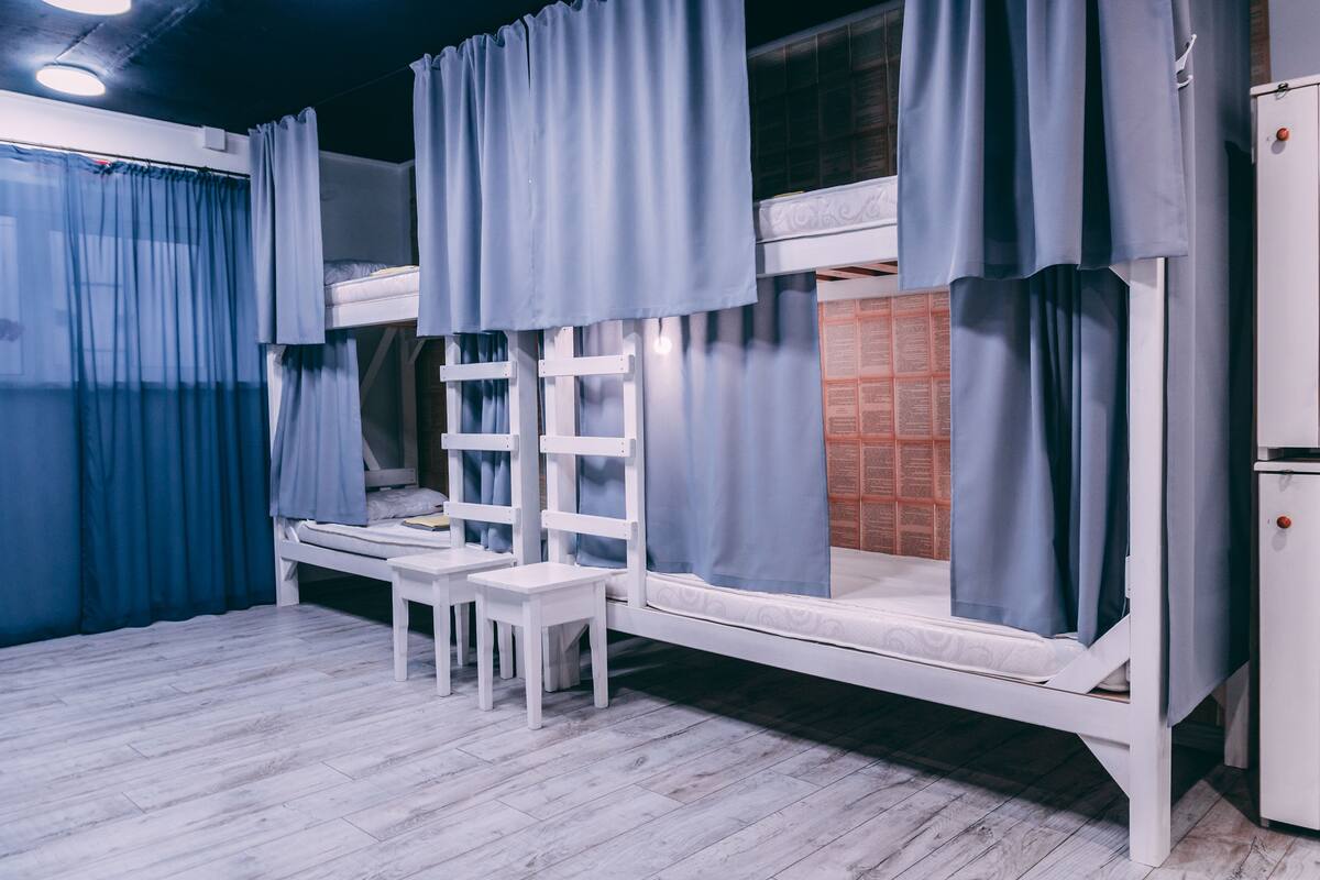 A bunk bed room with curtains, a small table, and a cabinet.