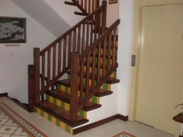 Eine Holztreppe mit Geländer, einem gemusterten Teppich und einer Tür mit Griff.
