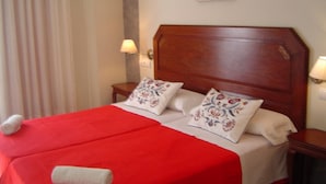 A neatly made bed with a red bedspread, two embroidered pillows, and a wooden headboard. - Hotel Al Andalus (Torrox)