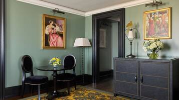 A room with a dark wooden cabinet, a painting, a lamp, and a table with chairs.