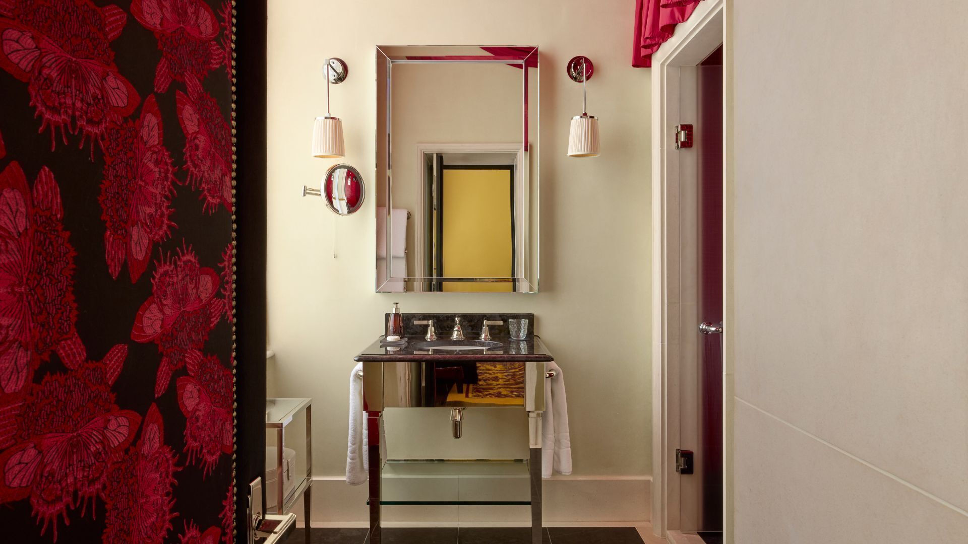 Un bany amb un lavabo amb vitrall, un mirall i dues làmpades de paret.