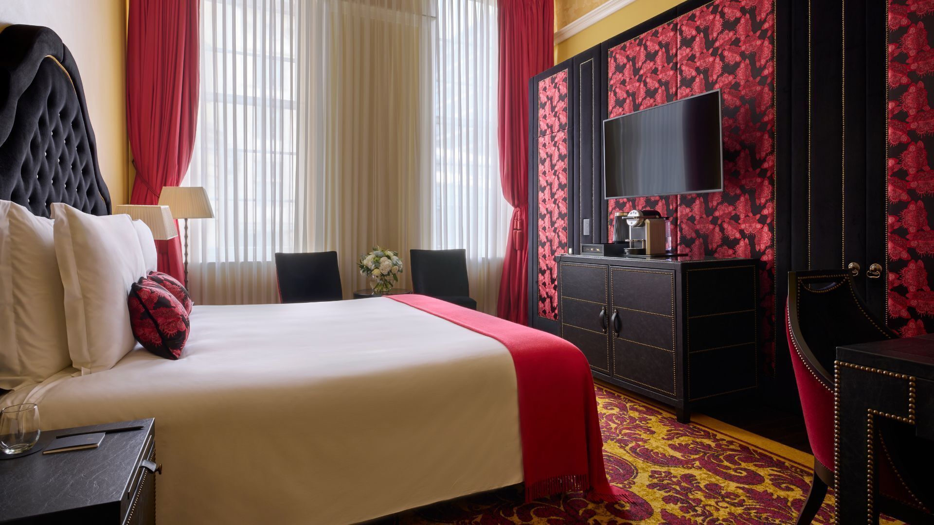 Una habitación de hotel con cama, escritorio, silla, televisor y armario.