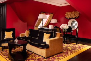 Ein Zimmer mit einer schwarz-beigen Couch, einem kleinen runden Tisch, einem Spiegel und einer roten Wand.