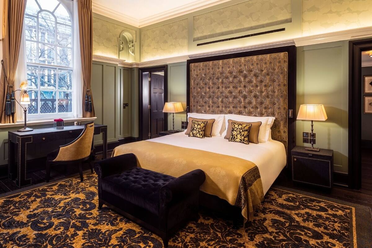 A hotel room with a large bed, a desk, a chair, and a window.