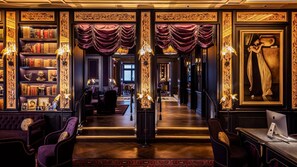 A grand hallway with ornate decorations, a library with bookshelves, and a desk with a computer. - L'oscar London (London)