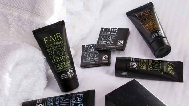 Various Fair Trade body care products including body lotion, soap, shampoo, and a shower gel, arranged on a white textured surface. - The Fleece Hotel (Richmond)