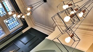 A modern interior with geometric light fixtures and a view of a window with a grid pattern. - The Fleece Hotel (Richmond)