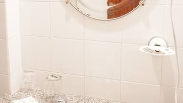 A bathroom with a sink, two faucets, a mirror, and a shower curtain rod.