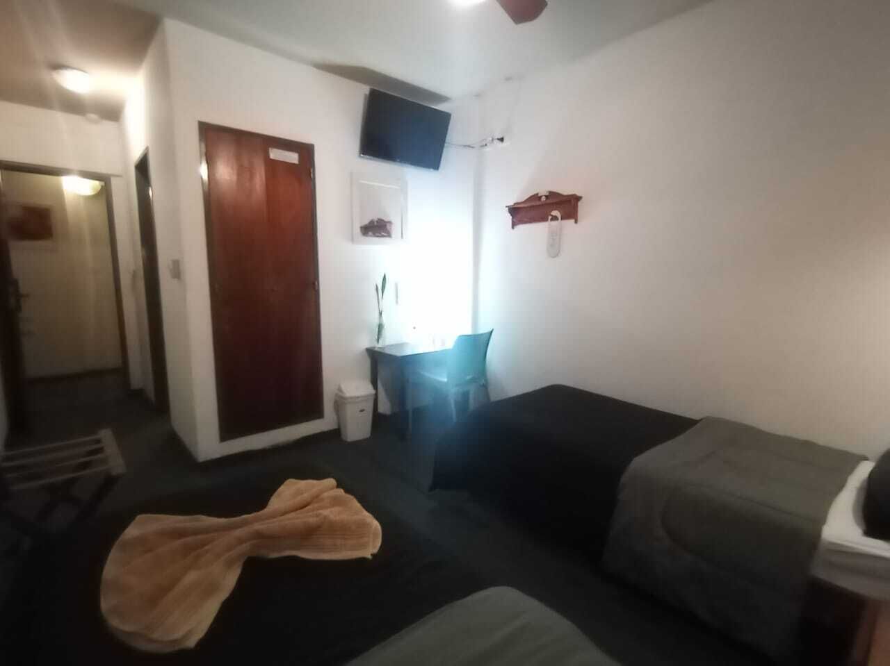 Ein kleiner, einfach eingerichteter Raum mit einem Bett, einem Schreibtisch und einem Stuhl.