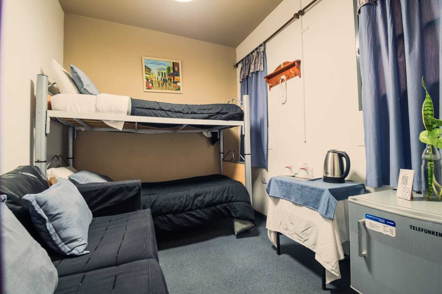 Un dormitorio con literas, un escritorio con hervidor y una planta pequeña.