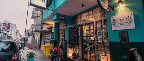 A hotel with a visible sign for a cafe, a motorcycle parked outside, and a number 365 sign on the wall.