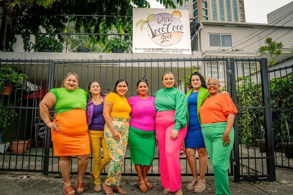 A group of people standing in front of a gated area with a sign that reads 'Hostal Loco Coco 2020'.